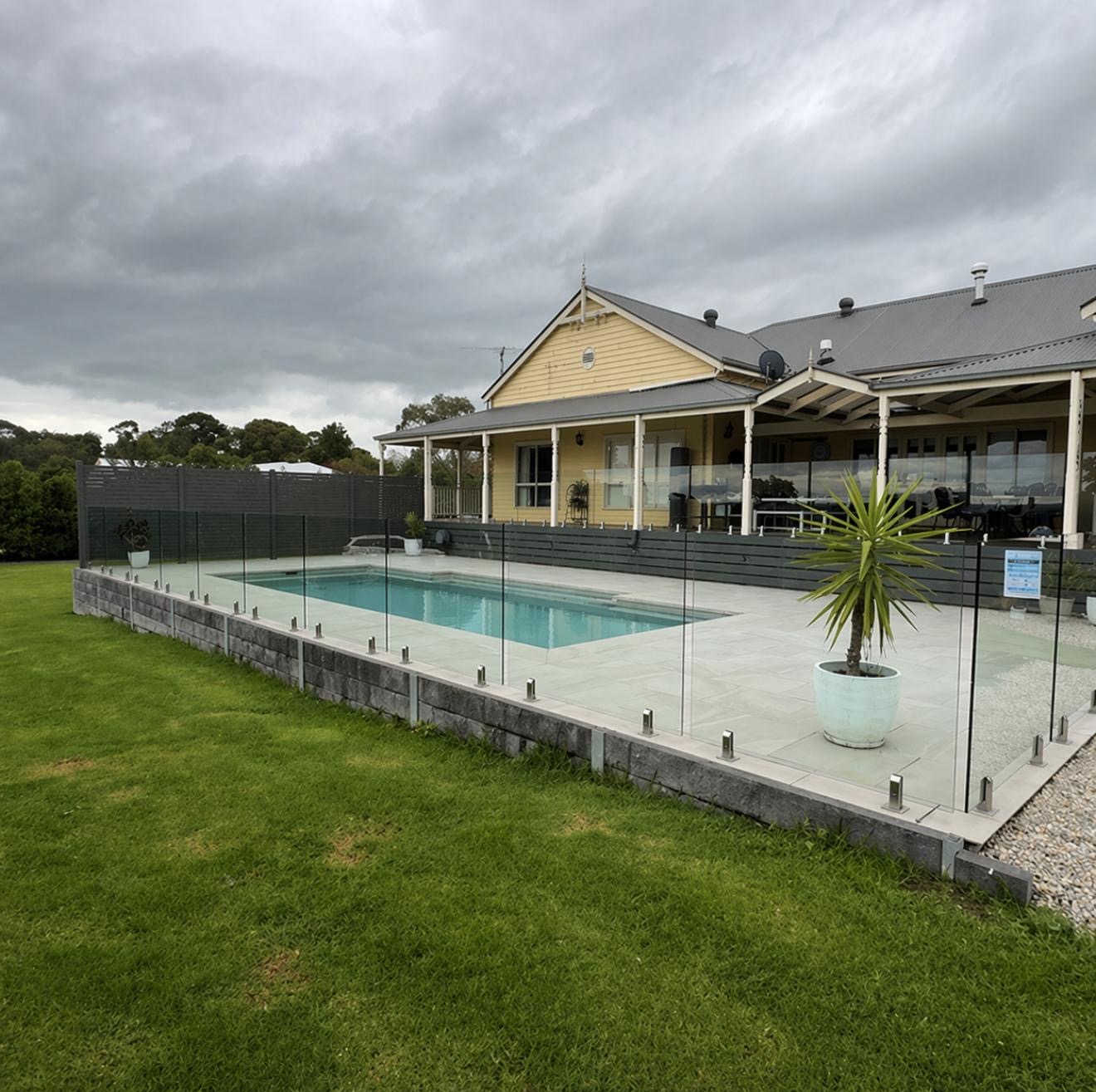 Glass pool fence inspection with hedge backdrop, Melbourne